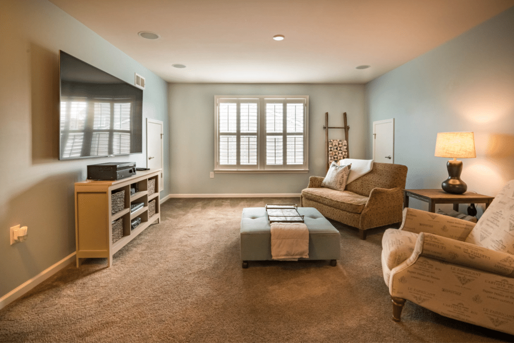 A comfortable home set at the ideal room temperature. Natural light spills through double hung windows into a living room with cozy furniture.